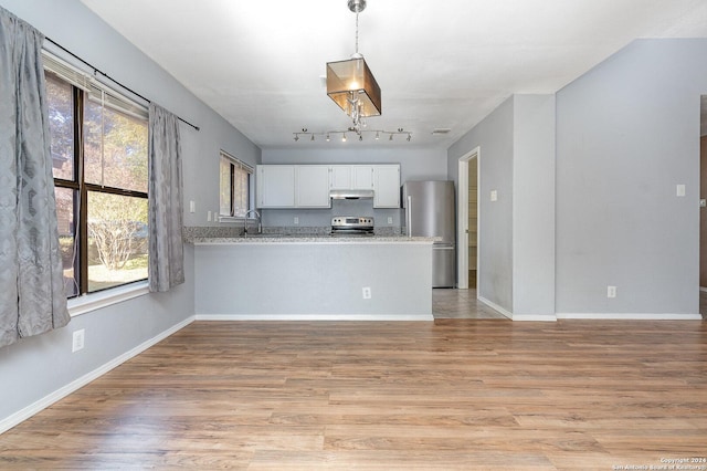 kitchen with white cabinets, kitchen peninsula, stainless steel appliances, and light hardwood / wood-style flooring