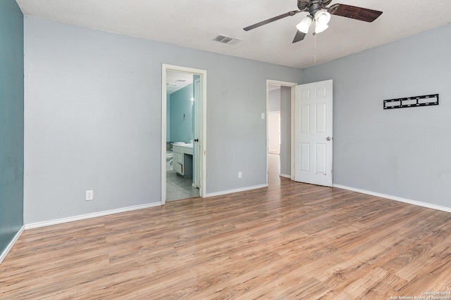 unfurnished bedroom featuring a textured ceiling, light wood-type flooring, ensuite bathroom, and ceiling fan