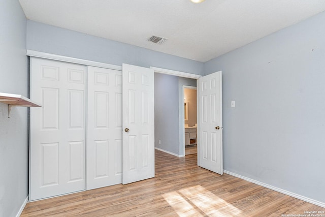 unfurnished bedroom with a closet, light hardwood / wood-style flooring, and a textured ceiling