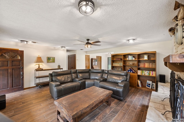 living room featuring hardwood / wood-style floors, a fireplace, ceiling fan, and a textured ceiling