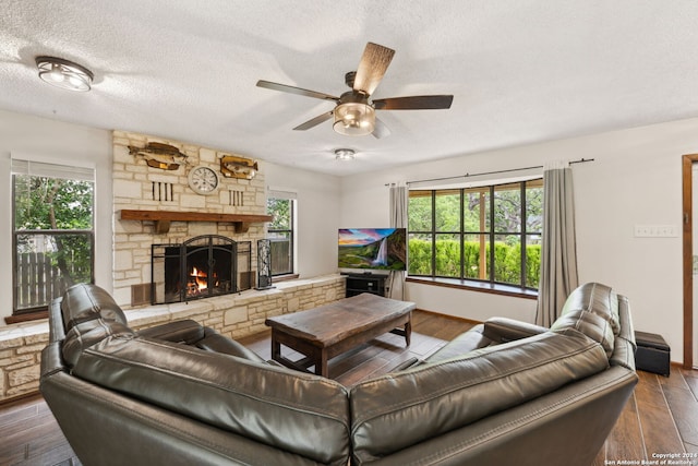 living room featuring ceiling fan, a fireplace, a textured ceiling, and hardwood / wood-style flooring