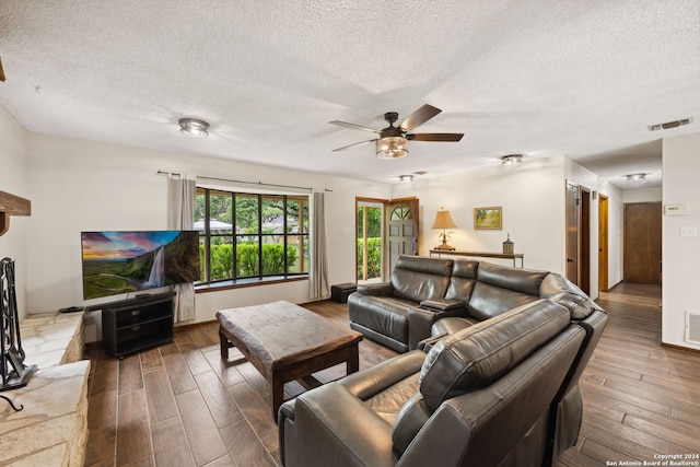 living room with ceiling fan, wood-type flooring, and a textured ceiling