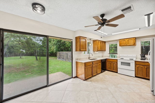 kitchen featuring a textured ceiling, white appliances, sink, and light tile patterned floors