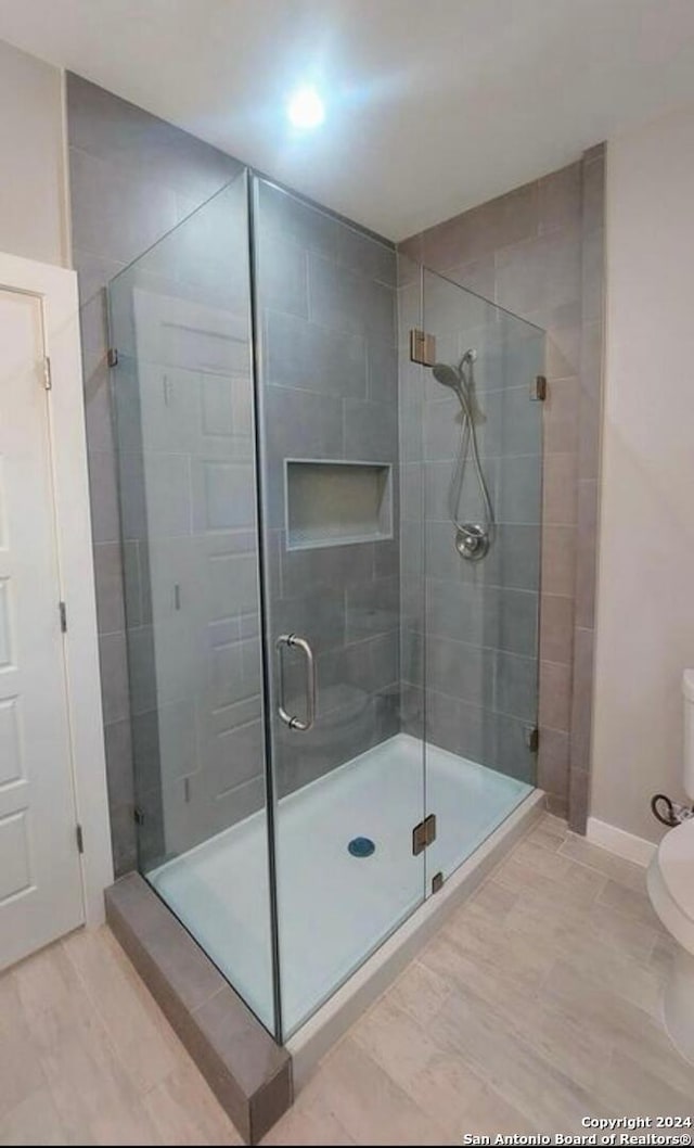 bathroom featuring toilet and a shower with shower door