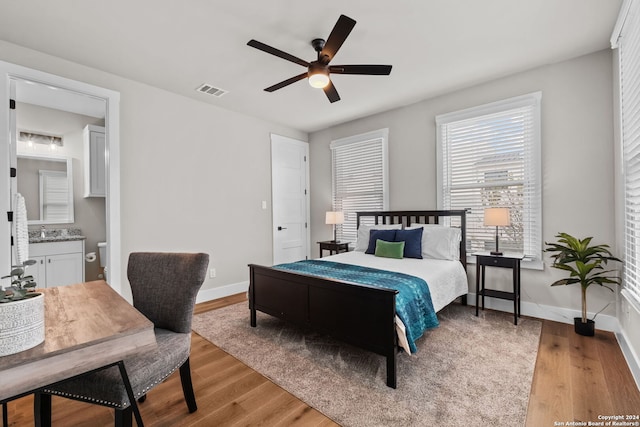 bedroom featuring hardwood / wood-style flooring, ensuite bathroom, ceiling fan, and sink