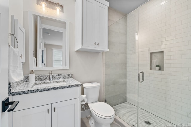 bathroom featuring vanity, toilet, and a shower with door