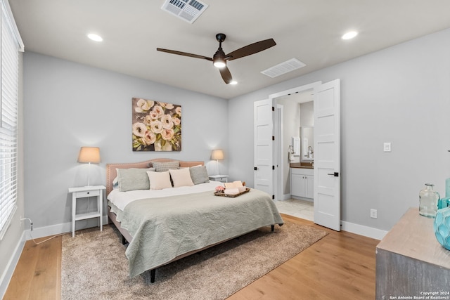 bedroom featuring ceiling fan, ensuite bath, and light hardwood / wood-style flooring