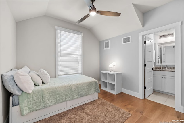 bedroom featuring connected bathroom, ceiling fan, sink, light hardwood / wood-style floors, and vaulted ceiling