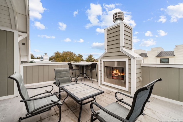 balcony featuring exterior fireplace and a patio area