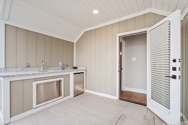 interior space with wood ceiling, vaulted ceiling, sink, stainless steel refrigerator, and light tile patterned flooring