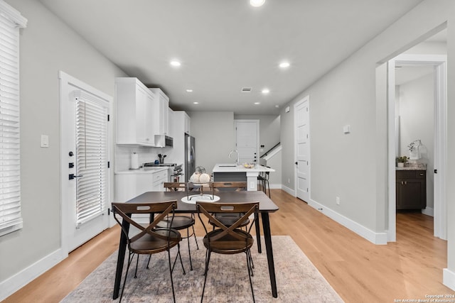 dining area with sink and light wood-type flooring