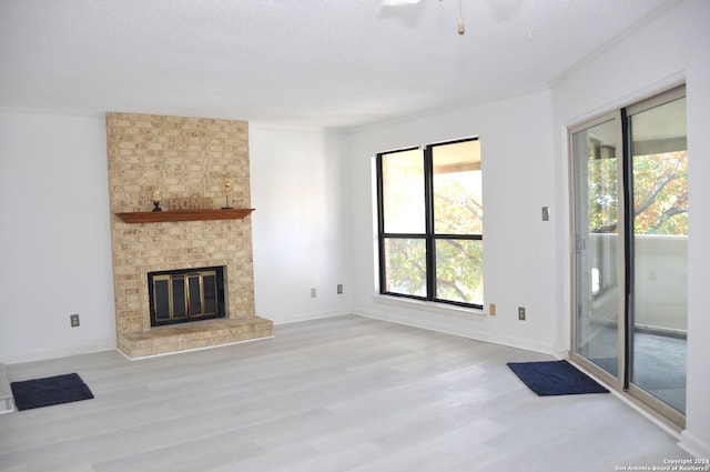 unfurnished living room featuring plenty of natural light, light wood-type flooring, and a brick fireplace