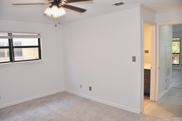 unfurnished room featuring a textured ceiling, ceiling fan, ornamental molding, and light carpet