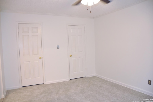 empty room featuring ceiling fan, light colored carpet, and a textured ceiling