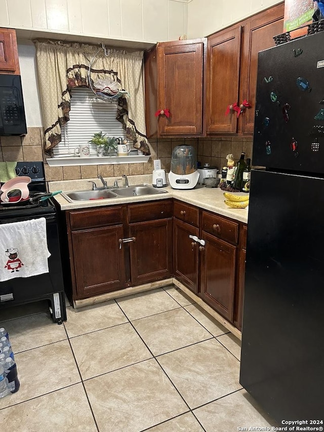 kitchen with tasteful backsplash, sink, light tile patterned floors, and black appliances