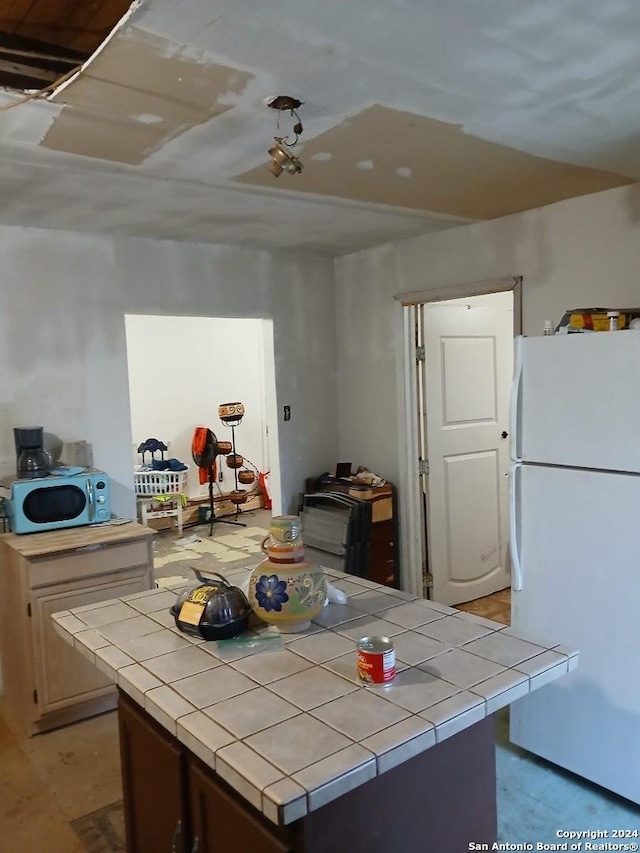 kitchen with white refrigerator and tile countertops