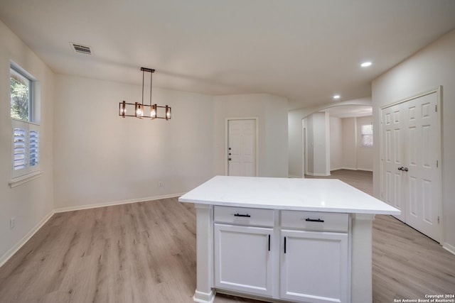 kitchen featuring decorative light fixtures, a center island, white cabinetry, and light hardwood / wood-style flooring