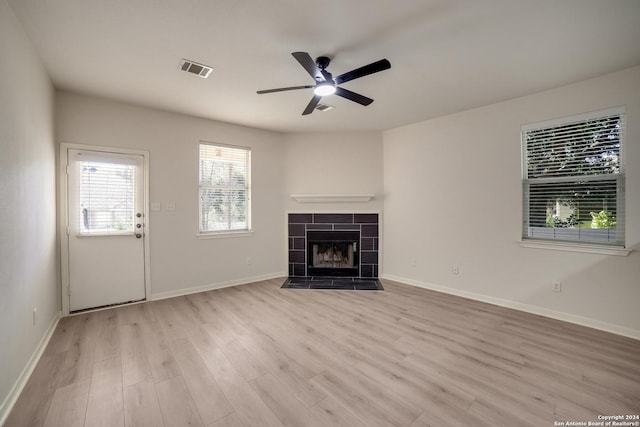 unfurnished living room featuring ceiling fan, light wood-type flooring, and a tile fireplace