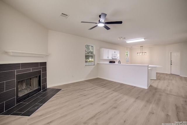 unfurnished living room with a fireplace, wood-type flooring, and ceiling fan