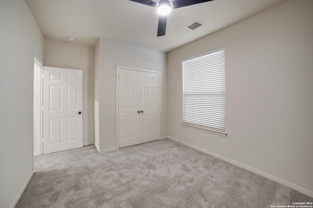 unfurnished bedroom with ceiling fan, light carpet, and a closet