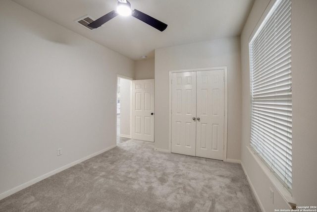 unfurnished bedroom featuring light carpet, a closet, and ceiling fan