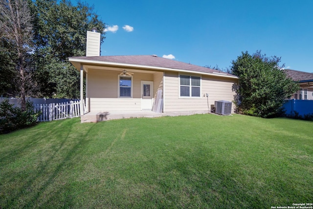 rear view of property featuring central AC, ceiling fan, and a yard