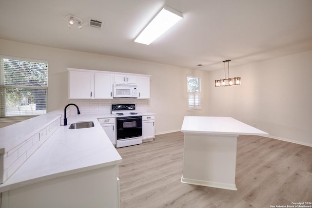 kitchen with white appliances, sink, hanging light fixtures, light hardwood / wood-style floors, and white cabinetry