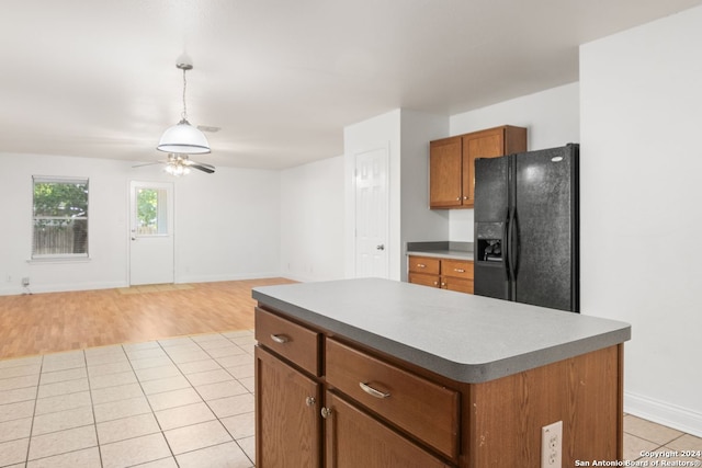 kitchen with ceiling fan, a center island, light hardwood / wood-style flooring, decorative light fixtures, and black fridge with ice dispenser