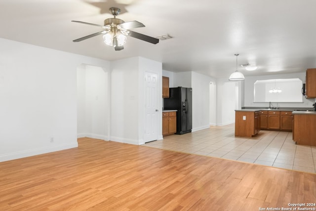 kitchen featuring light wood-type flooring, black refrigerator with ice dispenser, ceiling fan, sink, and pendant lighting