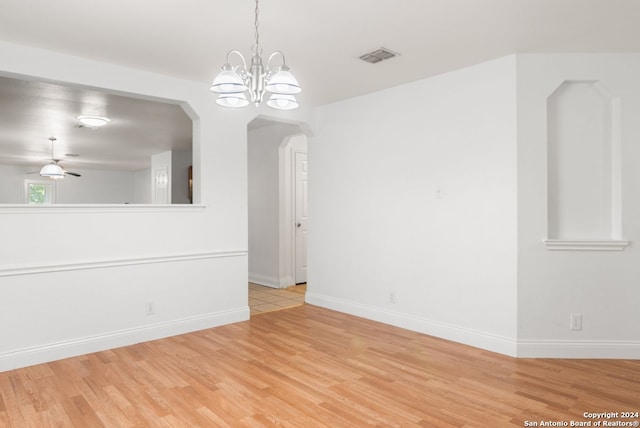 spare room featuring ceiling fan with notable chandelier and light wood-type flooring