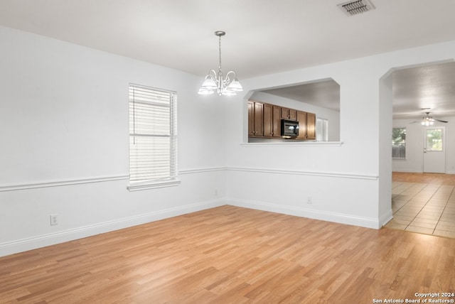 empty room featuring light hardwood / wood-style floors and ceiling fan with notable chandelier