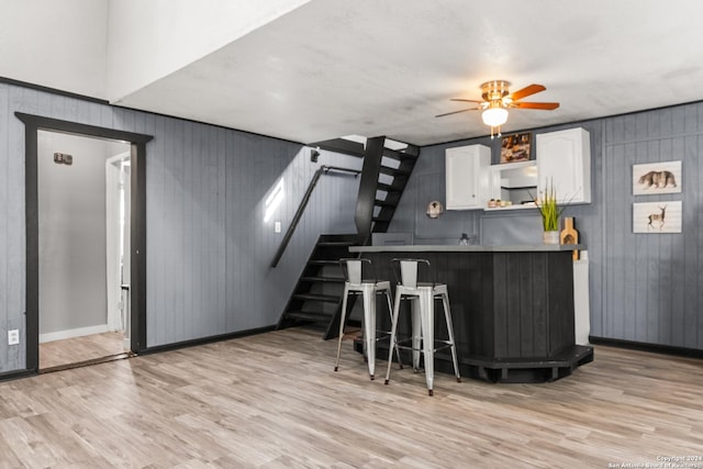 kitchen featuring a breakfast bar area, white cabinetry, and light hardwood / wood-style flooring