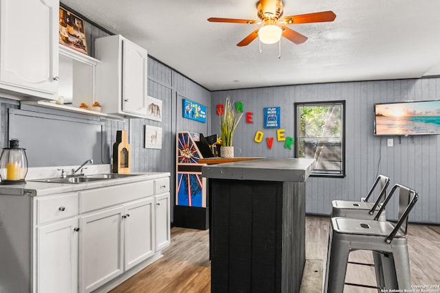 kitchen with white cabinets, ceiling fan, light wood-type flooring, and sink