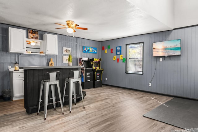 kitchen featuring white cabinets, light wood-type flooring, a kitchen bar, and ceiling fan