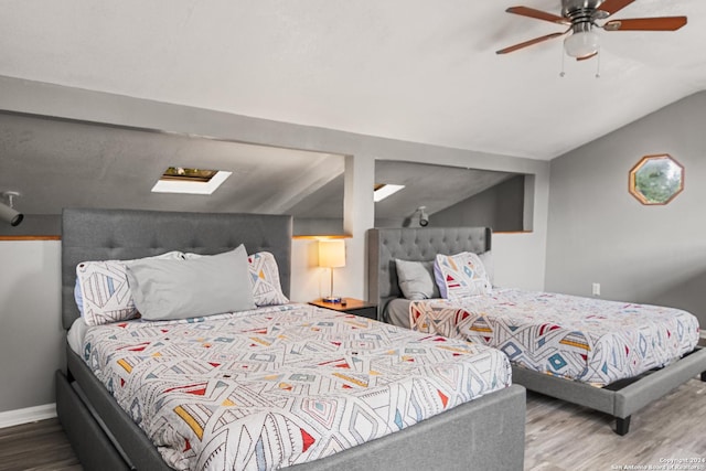 bedroom featuring hardwood / wood-style floors, ceiling fan, and vaulted ceiling with skylight