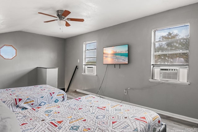 bedroom with multiple windows, ceiling fan, hardwood / wood-style floors, and cooling unit