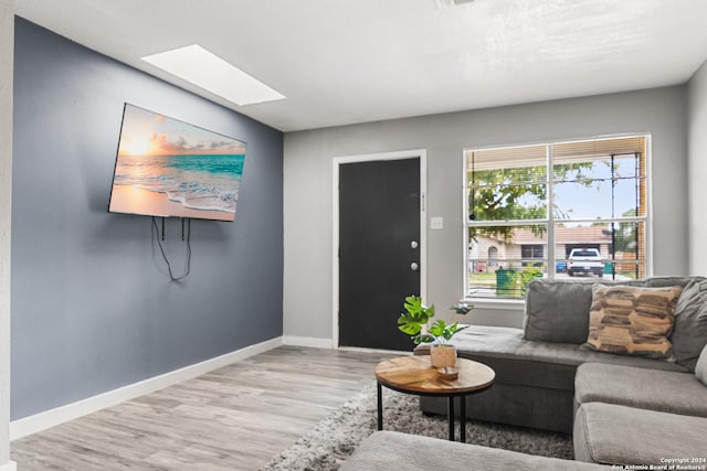 living room with a skylight and light hardwood / wood-style flooring