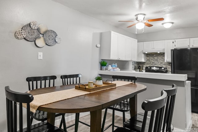 kitchen featuring backsplash, white cabinets, black appliances, light hardwood / wood-style flooring, and kitchen peninsula