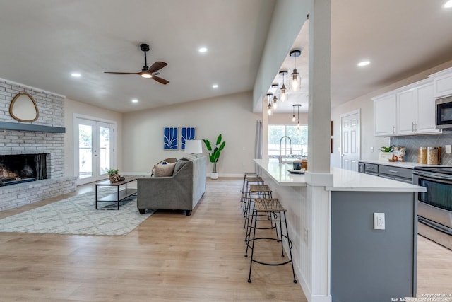 kitchen featuring white cabinetry, stainless steel appliances, light hardwood / wood-style floors, a kitchen bar, and a kitchen island with sink