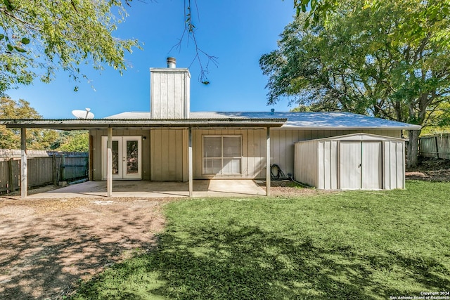 rear view of house with a lawn, french doors, a patio, and a storage shed