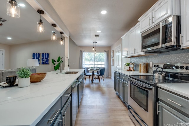 kitchen featuring backsplash, stainless steel appliances, sink, pendant lighting, and white cabinetry