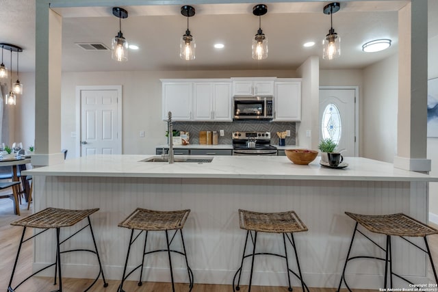 kitchen featuring white cabinets, decorative light fixtures, and stainless steel appliances