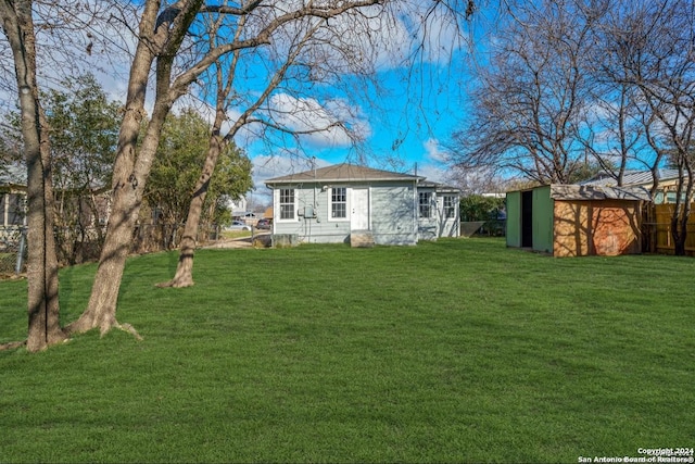 back of property with a yard and a storage shed