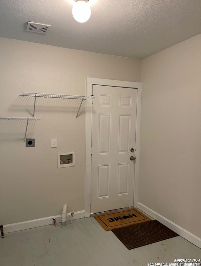 laundry room featuring electric dryer hookup, hookup for a washing machine, a textured ceiling, and light hardwood / wood-style flooring