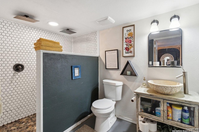 bathroom featuring a tile shower, toilet, and sink