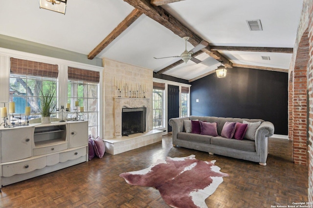 living room featuring lofted ceiling with beams, a healthy amount of sunlight, a tile fireplace, and dark parquet floors