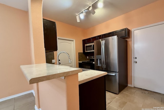 kitchen with sink, kitchen peninsula, track lighting, a breakfast bar, and appliances with stainless steel finishes