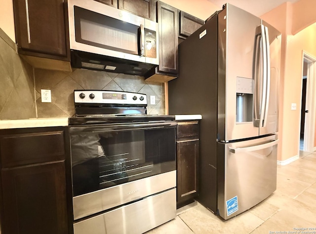 kitchen featuring decorative backsplash, dark brown cabinets, light tile patterned floors, and stainless steel appliances