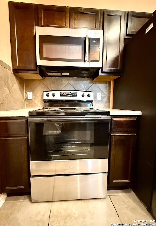 kitchen featuring tasteful backsplash, dark brown cabinets, light tile patterned floors, and stainless steel appliances