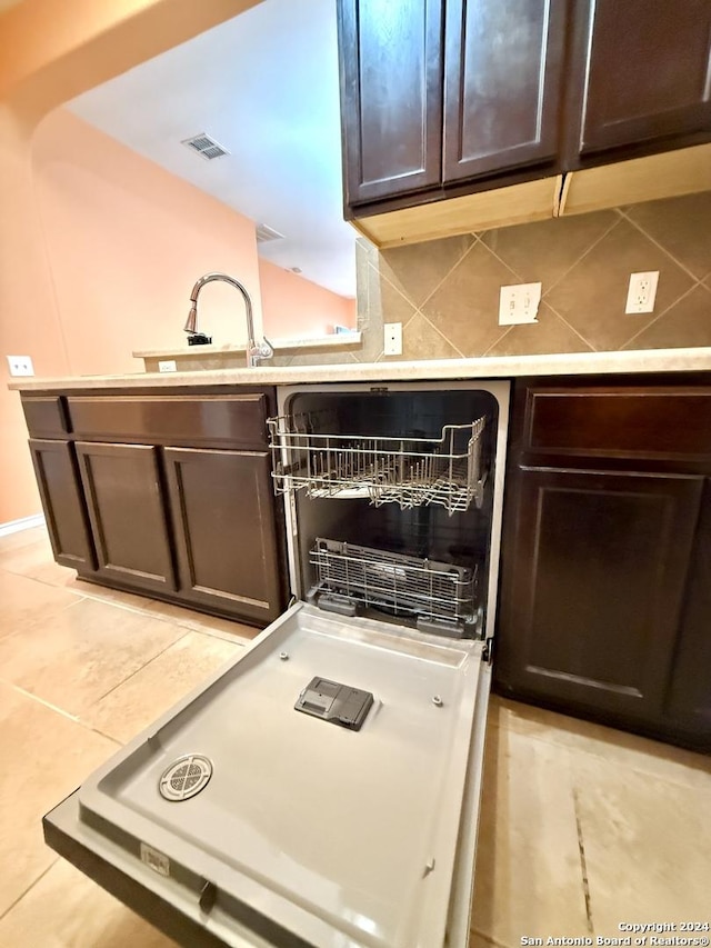 kitchen featuring dark brown cabinets, tasteful backsplash, light tile patterned floors, and sink